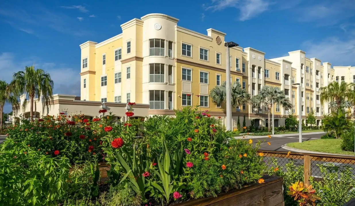 Yellow luxury apartment buildings surrounded by tropical landscaping and colorful flower beds