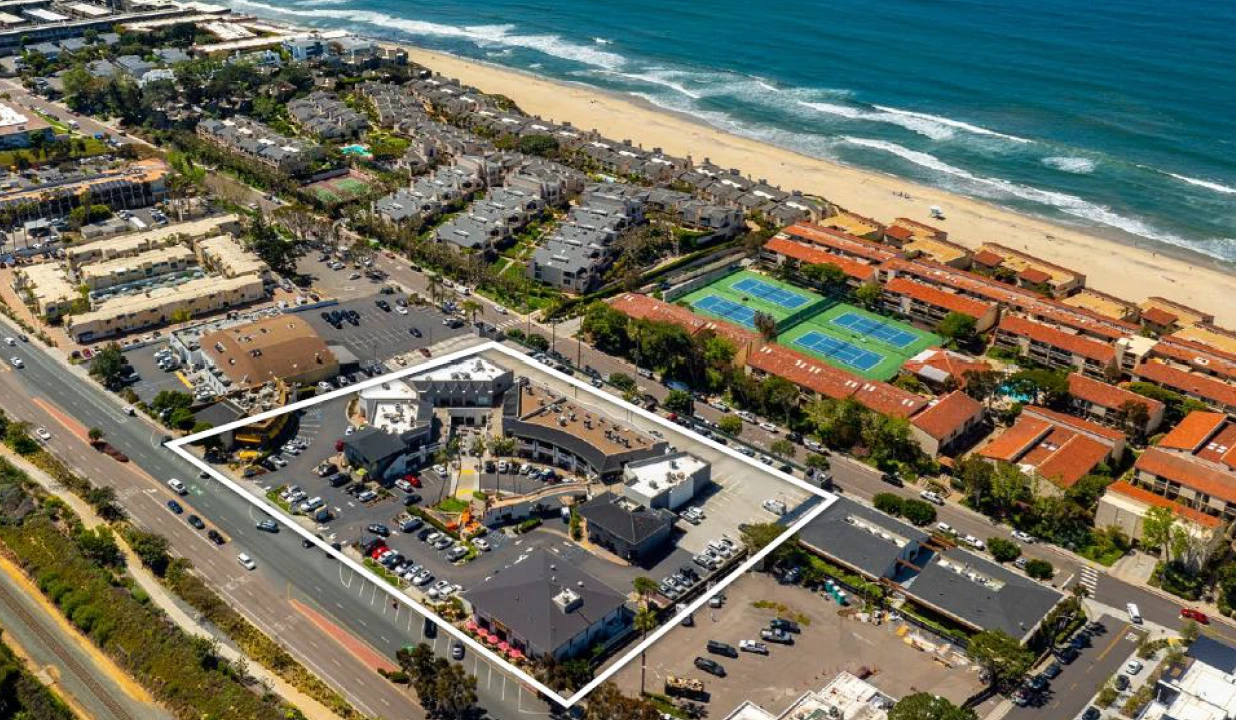 Coastal walking path overlooking the Pacific Ocean with crashing waves and rugged landscape